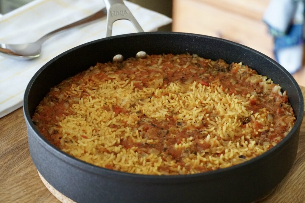 The skillet of Spanish rice resting off the heat.
