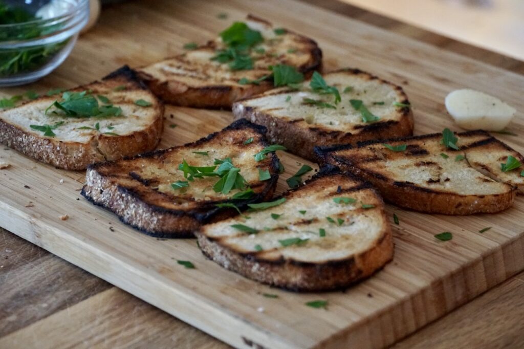 Grilled slices of sourdough bread brushed with oil and rubbed with garlic.