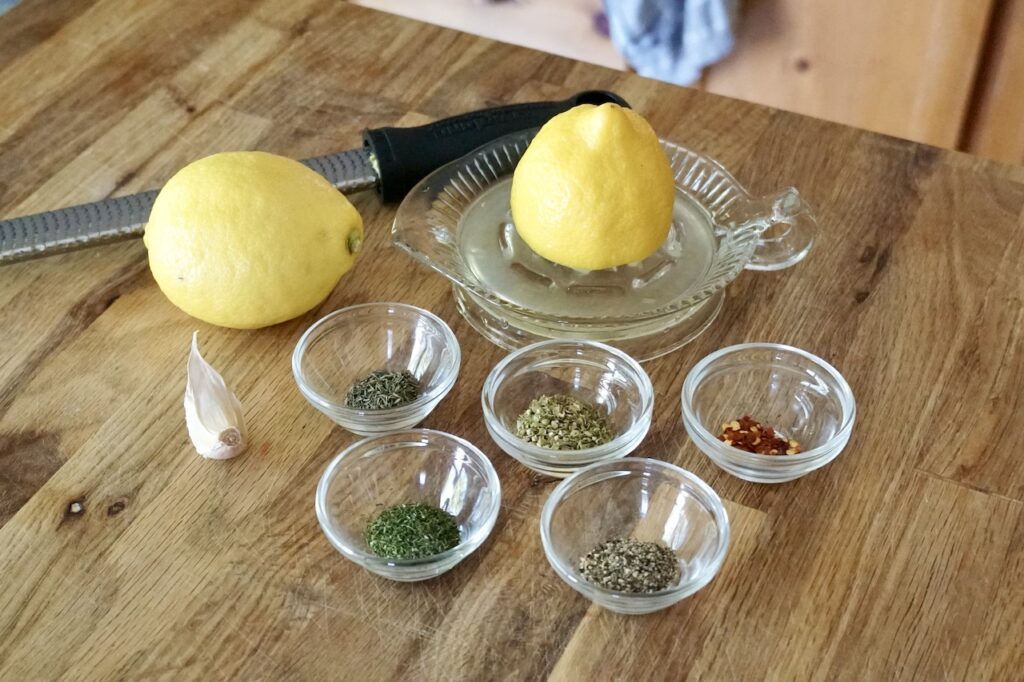 Assorted dried herbs, chili flakes, garlic and a whole lemon.