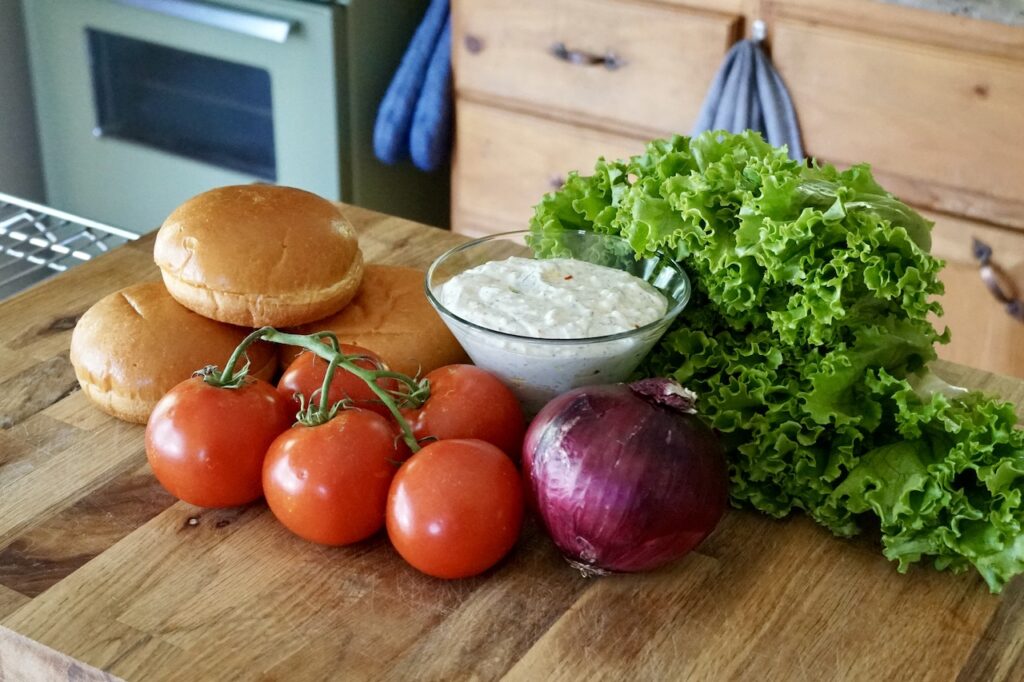 Hamburger buns, tomatoes, red onion, curly lettuce and feta cheese dip.