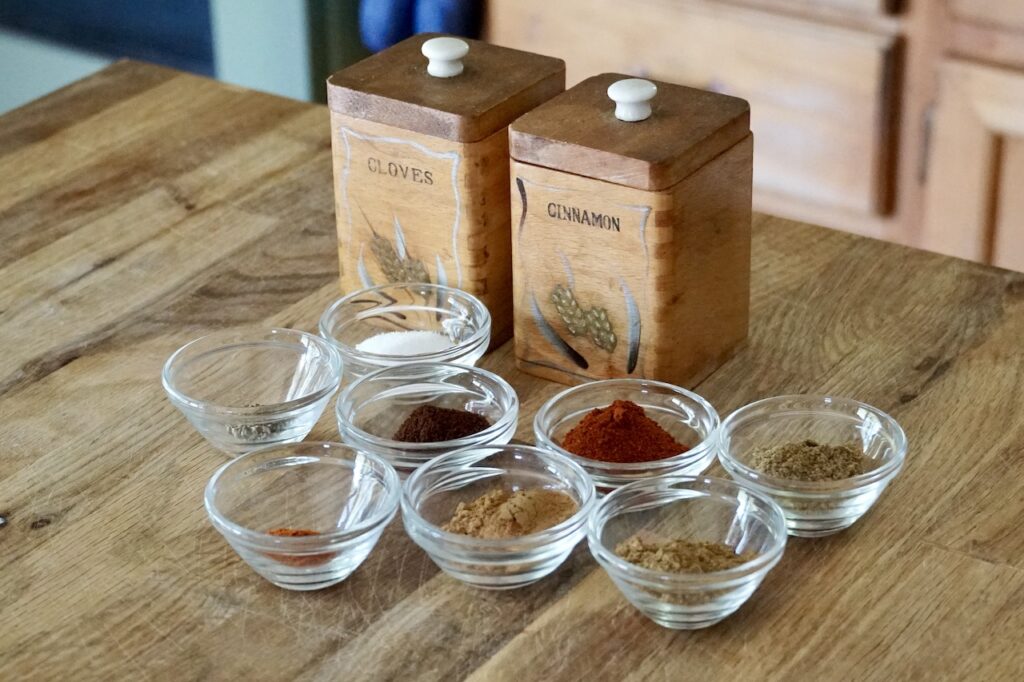 Assorted spices including; cinnamon, cumin, cloves, coriander, paprika, cayenne, salt and pepper.