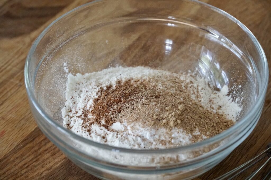 The dry mix ingredients spilled into a glass bowl, ready to be combined.