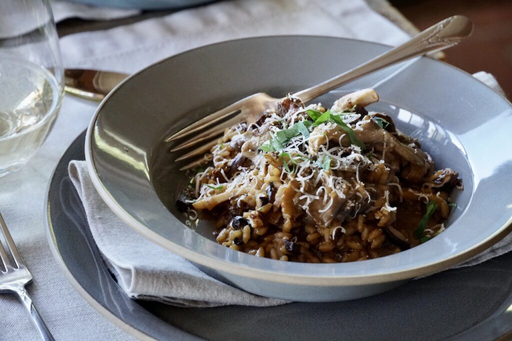A bowl of wild mushroom risotto topped with sautéed mushrooms, Parmesan and chopped Italian flat-leaf parsley.