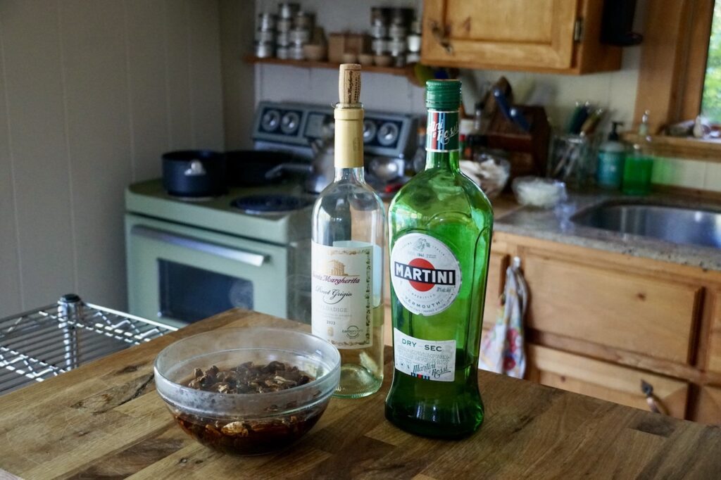 Bottles of dry vermouth, white wine and the liquid from the soaked porcini mushrooms.