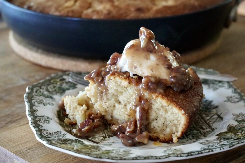A wedge of Apple Skillet Cake served with vanilla ice cream and butter pecan sauce.