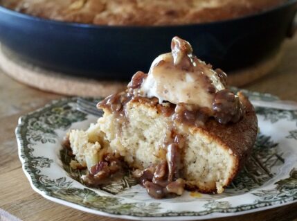 A wedge of Apple Skillet Cake served with vanilla ice cream and butter pecan sauce.