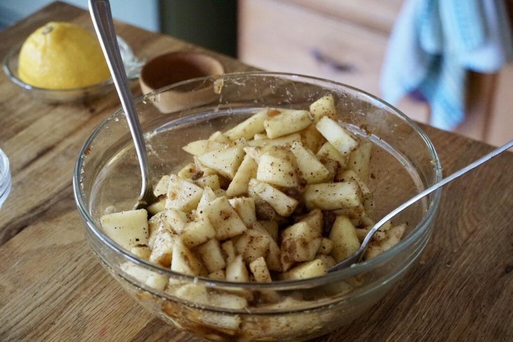 The apple mixture tossed in a bowl, ready to be incorporated into the cake batter.