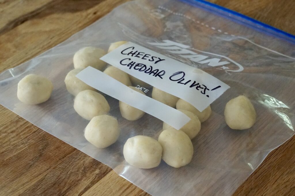 Baked Cheddar Olives stored in a storage bag, ready to be frozen.