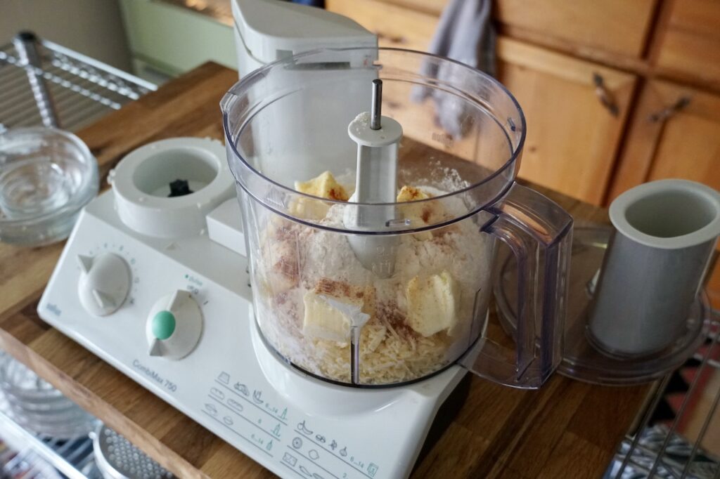A food processor filled with the ingredients to make the cheddar pastry for the olives.