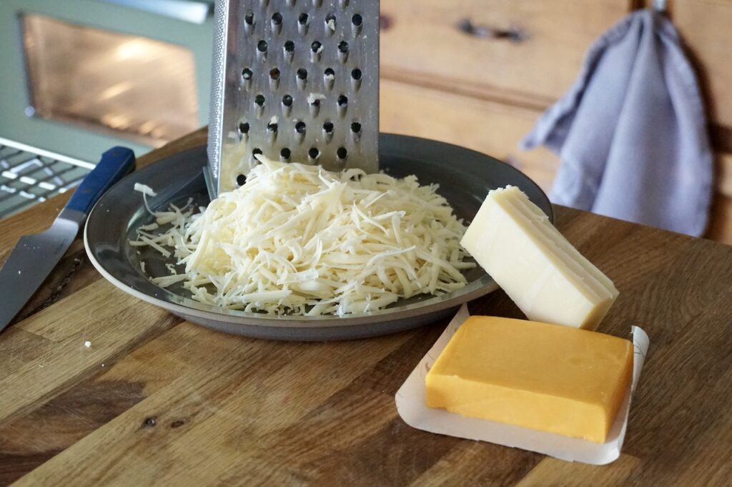 Freshly grated gruyère cheese and a block of agged cheddar.