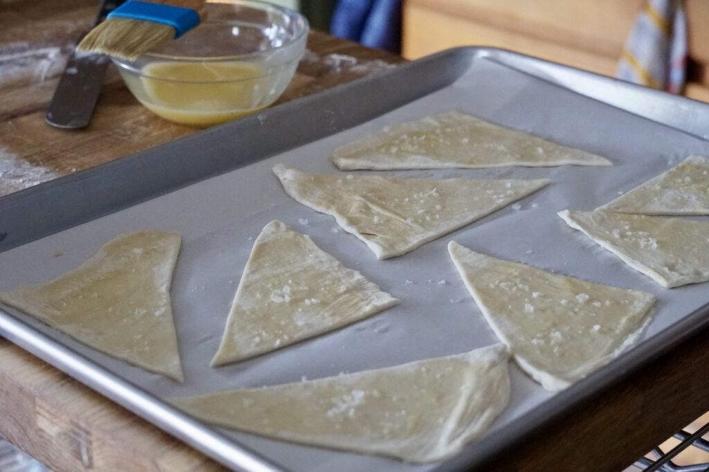 A baking tray with the unbaked puff pastry triangles.