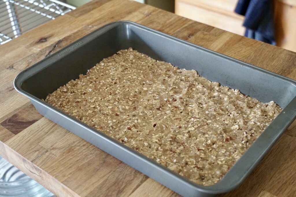 A rectangular baking dish with a rolled oat and pecan base.