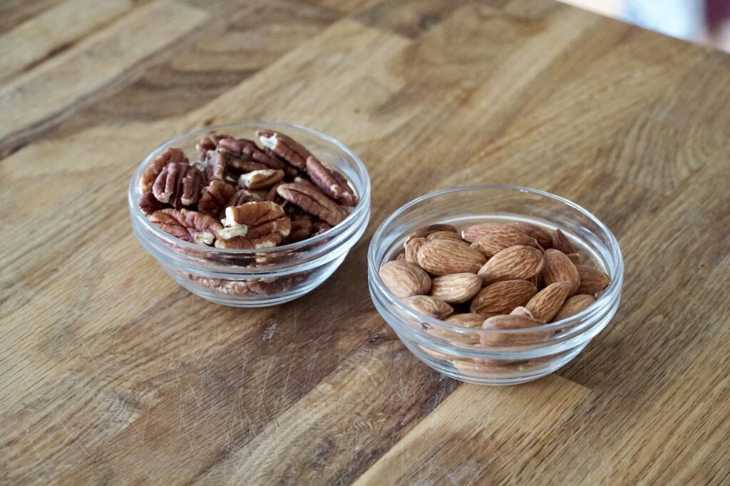 Bowls of whole almonds and pecan pieces.