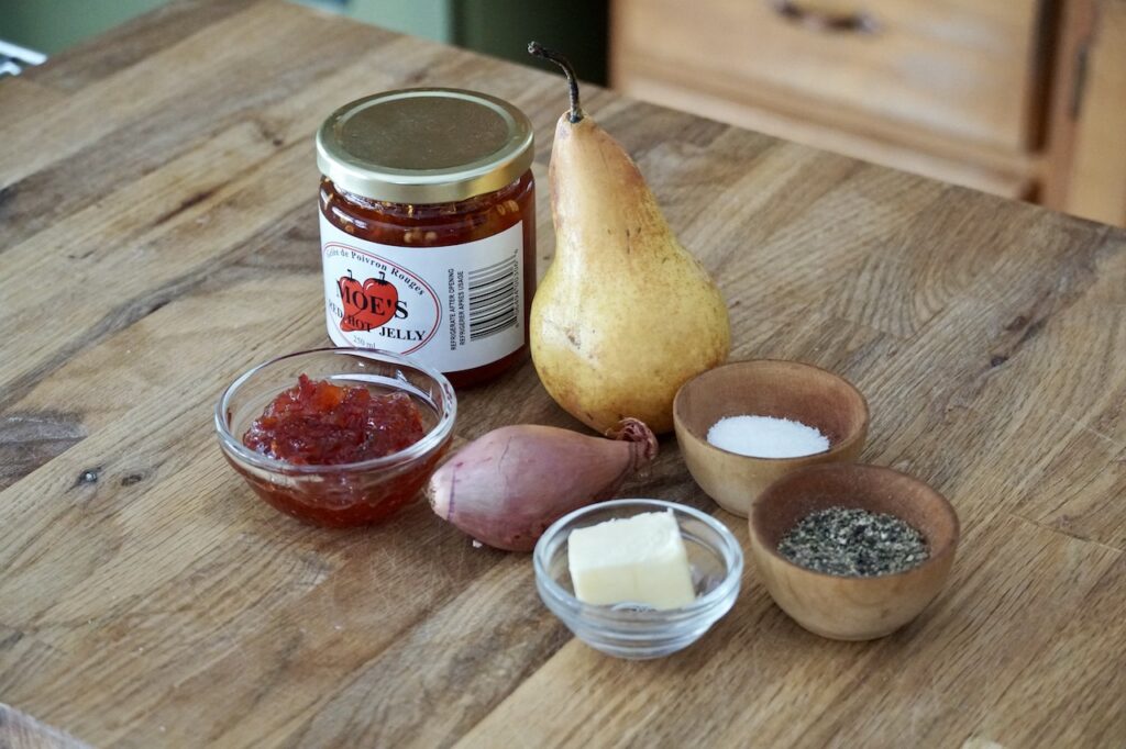 A jar of red pepper jelly, a pear, shallot, butter and seasoning.