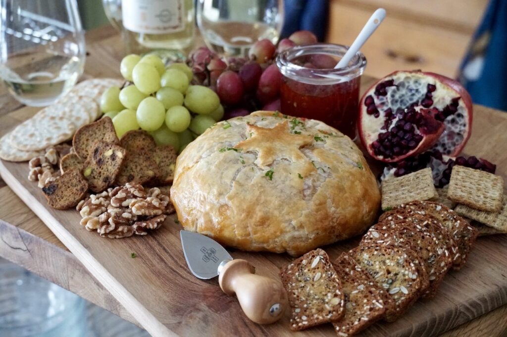 Baked Brie en Croute presented with crackers, fresh fruit and walnuts.