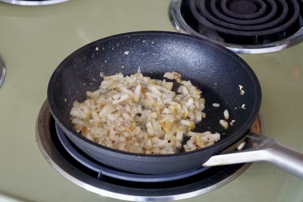A small skillet containing the sauté of pear with butter and shallot.