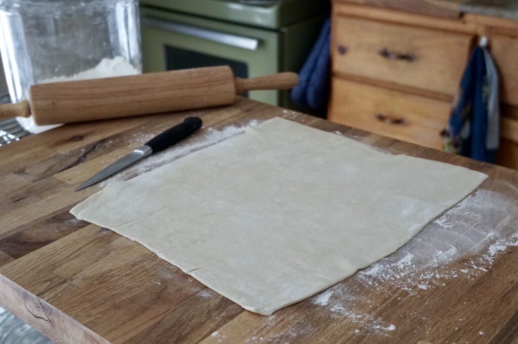A large sheet of puff pastry tolled out on a lightly floured surface.