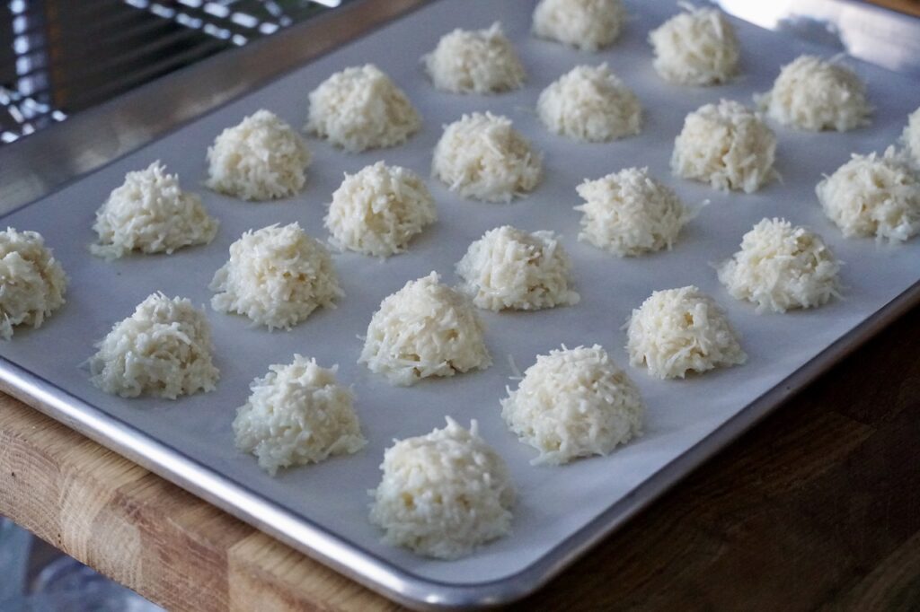 The coconut macaroons portioned out on a parchment lined baking sheet.