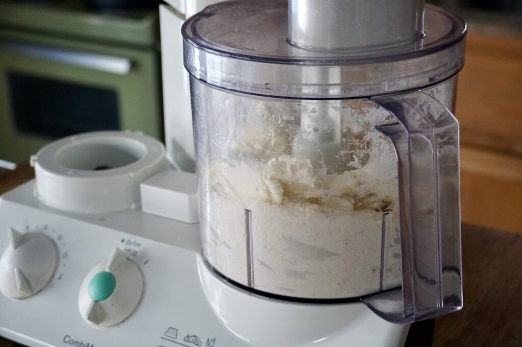 The cookie dough assembled in the canister of a food processor.