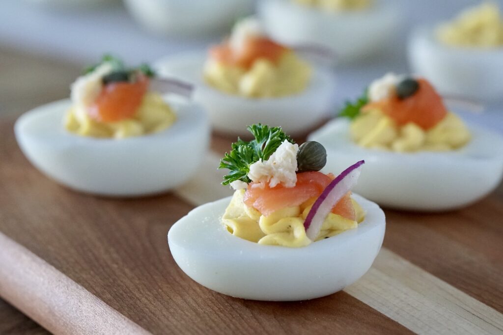 A deviled egg garnished with smoked salmon, red onion, caper and horseradish.