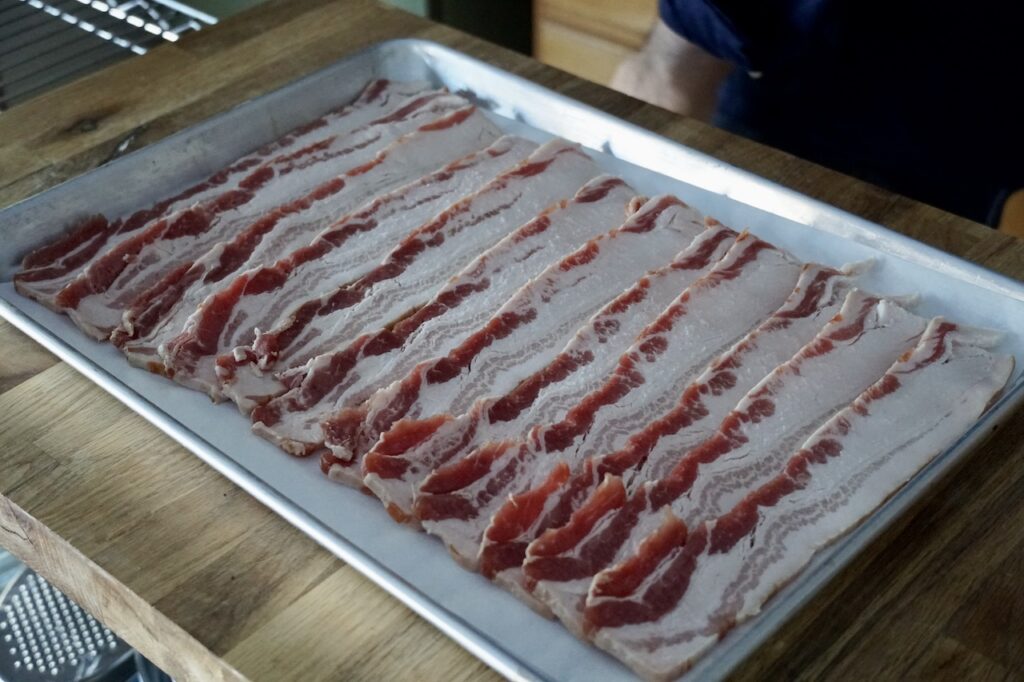 A baking sheet covered with parchment paper then, rashers of bacon.