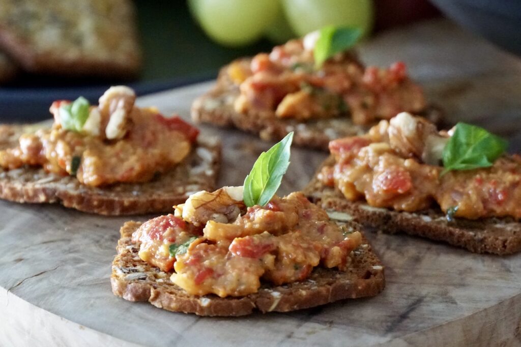Roasted Red Pepper Dip served as hors d'oeuvres on fancy crackers.