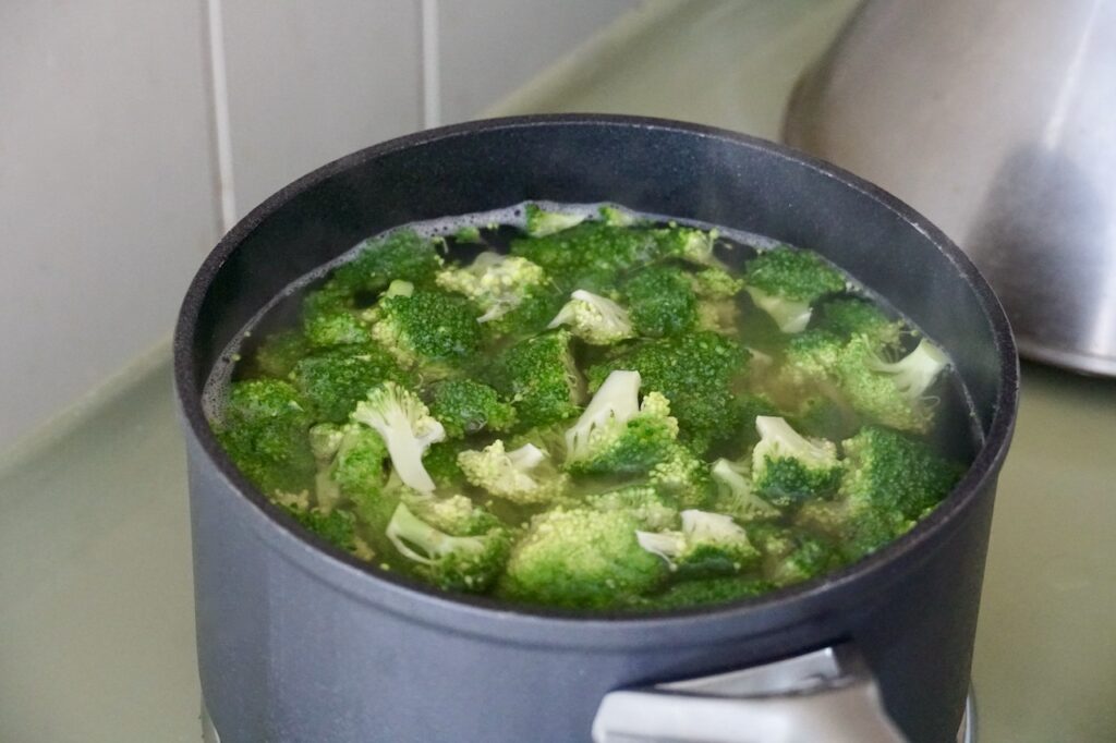 A medium-sized saucepan filled with broccoli being blanched.