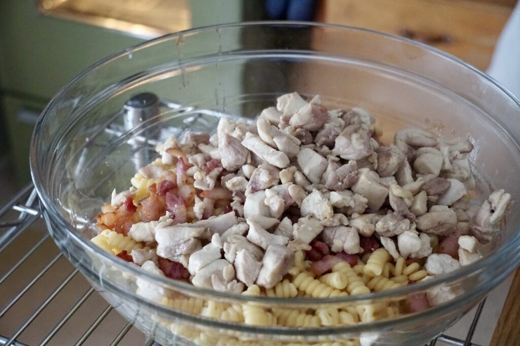 A big bowl filled with the pasta, cooked chicken and bacon.
