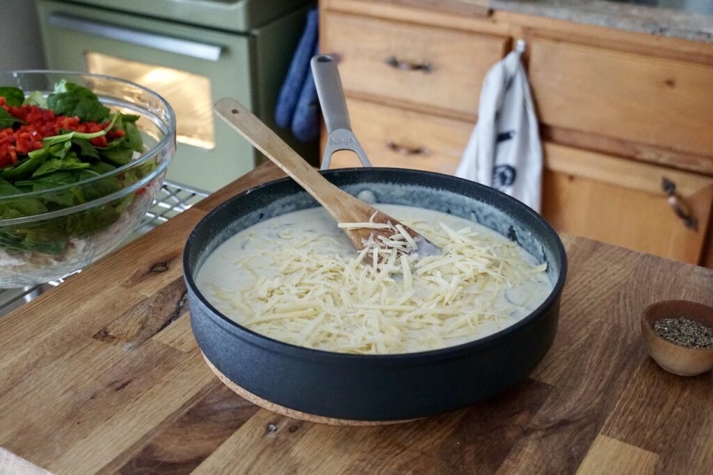 The creamy cheese sauce resting in a large skillet ready to be stirred together.