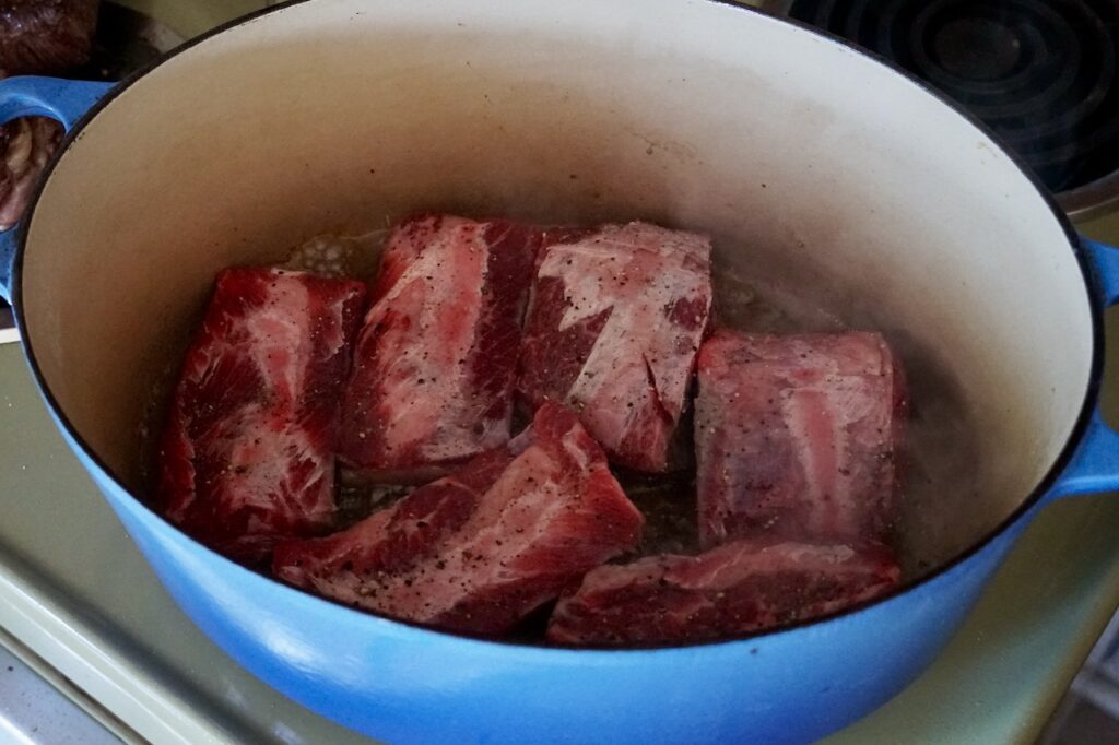 One batch of short ribs being seared in a Dutch oven.