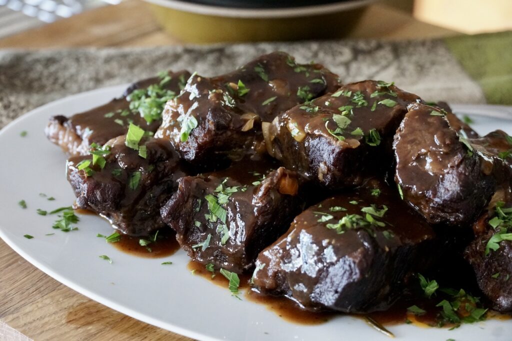 Braised beef short ribs served on a platter complete with the flavourful sauce.