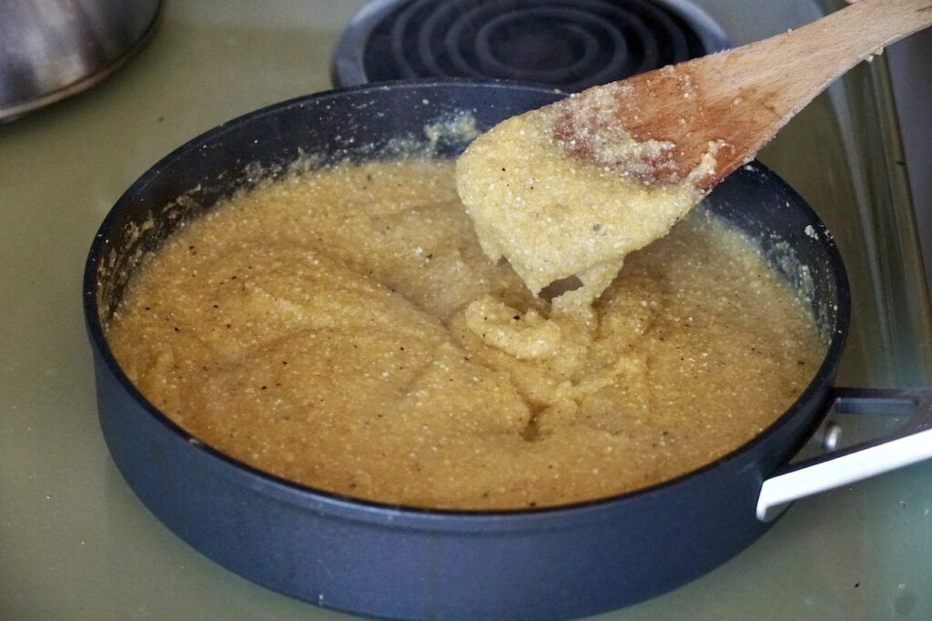 The cornmeal is cooked in a large skllet.