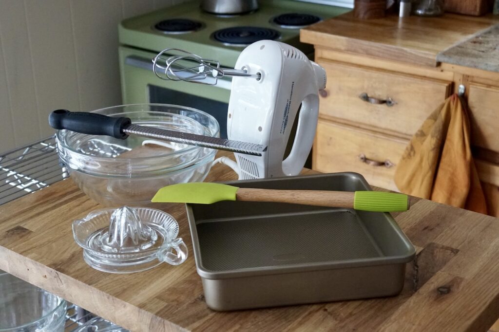Equipment needed to make the cake include bowls, a juicer, zester, pan, spatula and hand mixer.