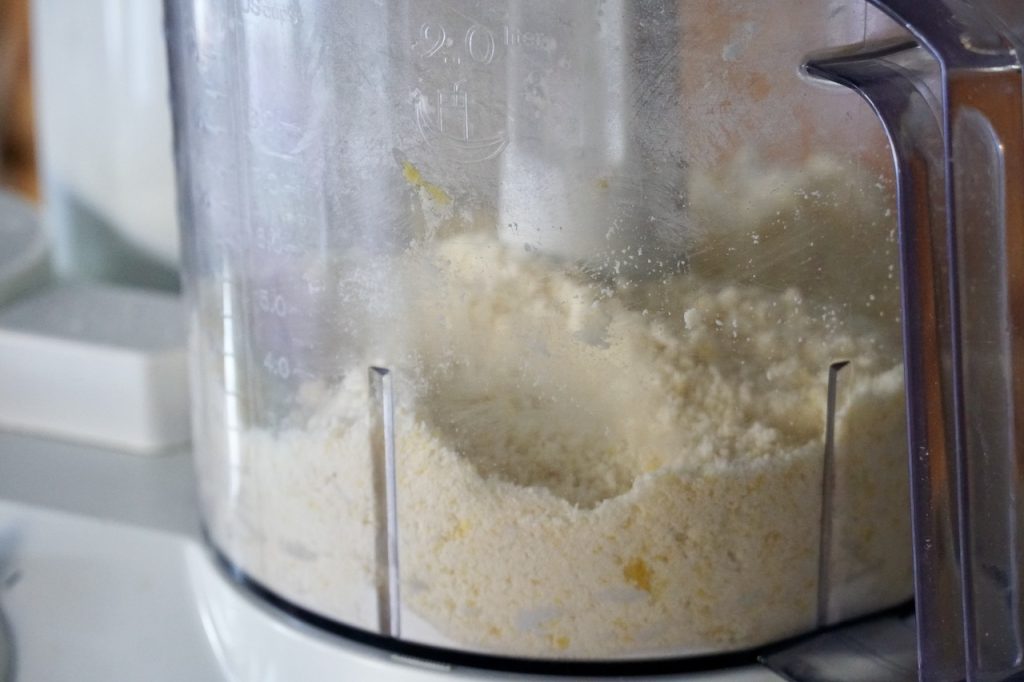 A food processor containing the ingredients for the shortcrust pulsed to a fine crumb.