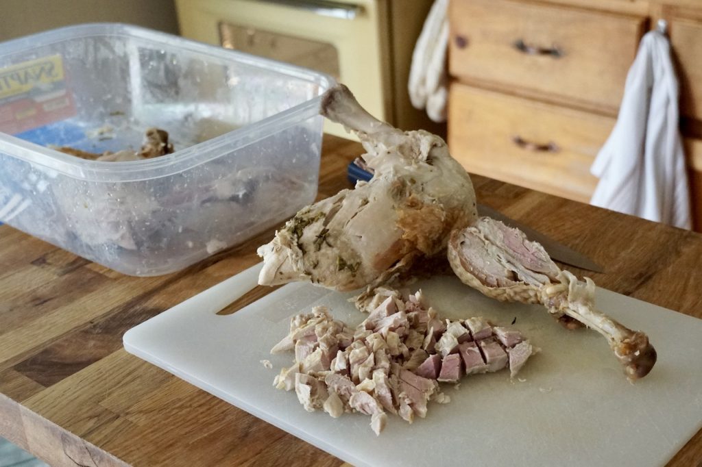 Leftover turkey cut up on a cutting board; both light and dark meat presented.
