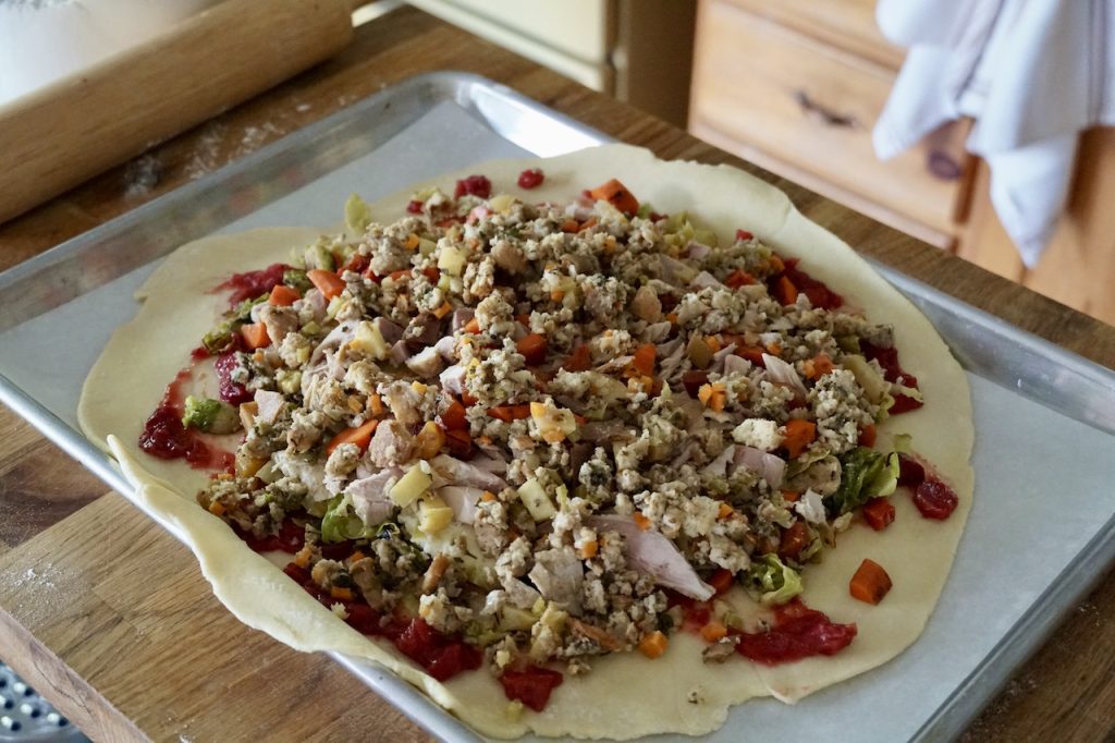 All of the ingredients from leftover turkey dinner arranged on a large round of homemade pastry.