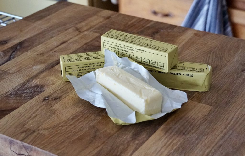 Four sticks of salted butter opened on the work surface, coming to room temperature.