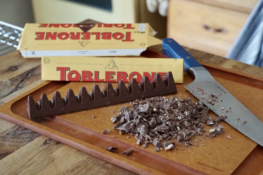 Two Toblerone chocolate bars chopped up on a cutting board.
