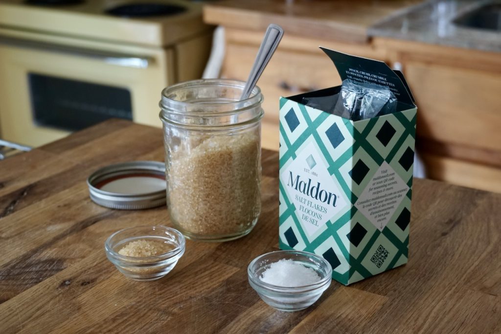 A jar of sanding sugar and a box of sea salt flakes.