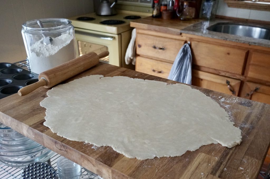 The pastry for the pies rolled out on a wooden work surface.