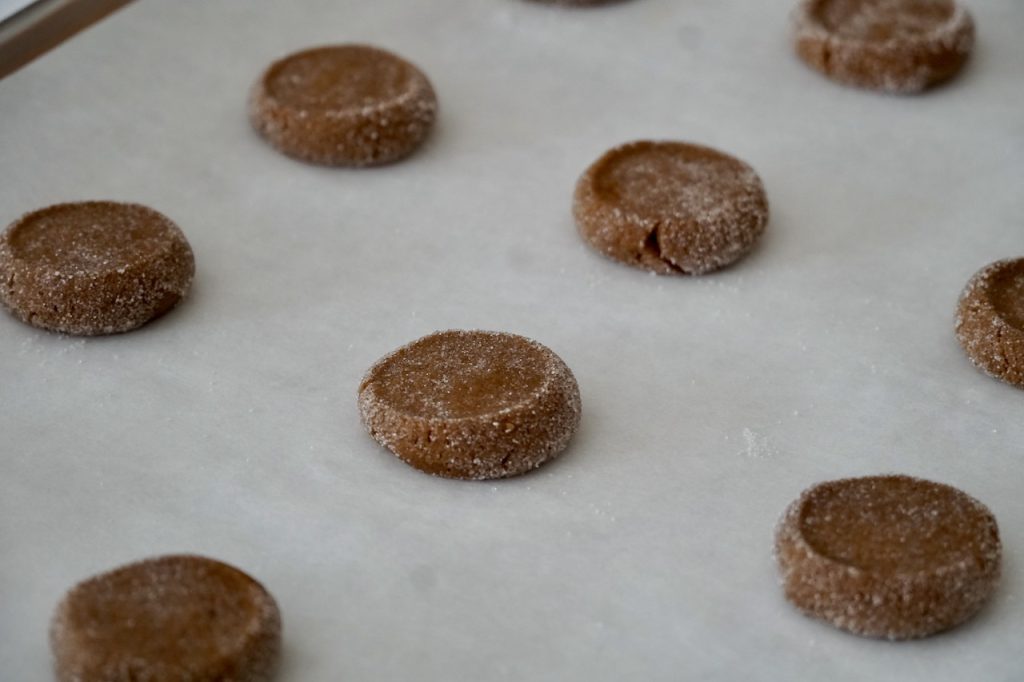 A baking tray of ginger cookies after being flattened.