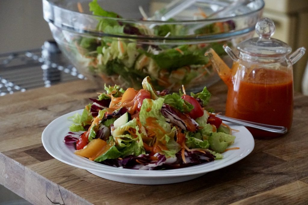 Fresh salad of assorted greens and veggies served on a plate with a delicious French dressing recipe.