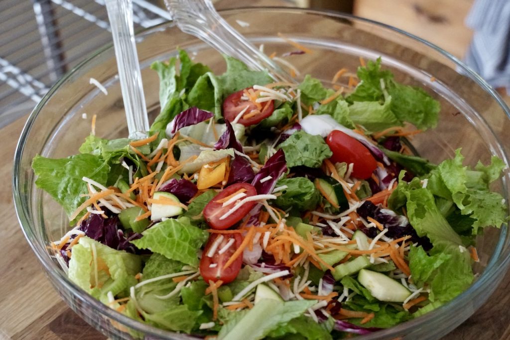 A bowl filled with a fresh salad made with assorted greens and vegetables.