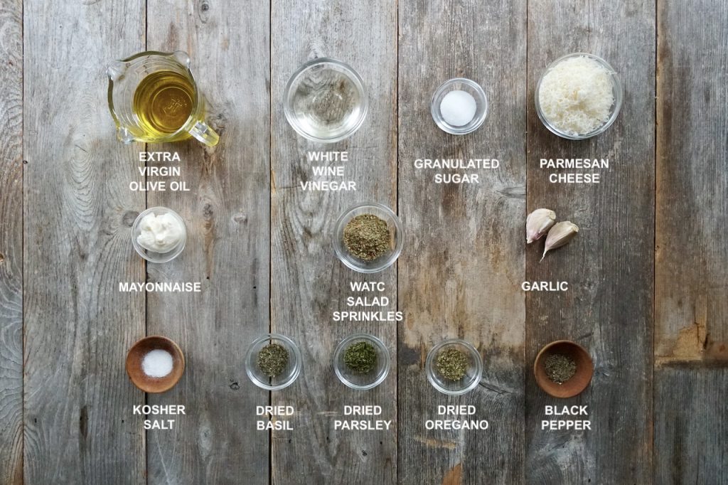 All of the ingredients needed to make the best homemade Italian dressing including: oil, white wine vinegar, garlic, salt, pepper, sugar, mayonnaise and dried seasoning and herbs.