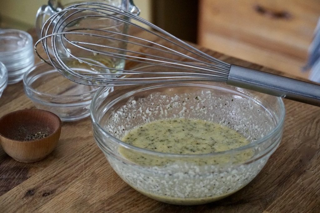 A bowl of homemade Italian dressing made using a wire whisk.