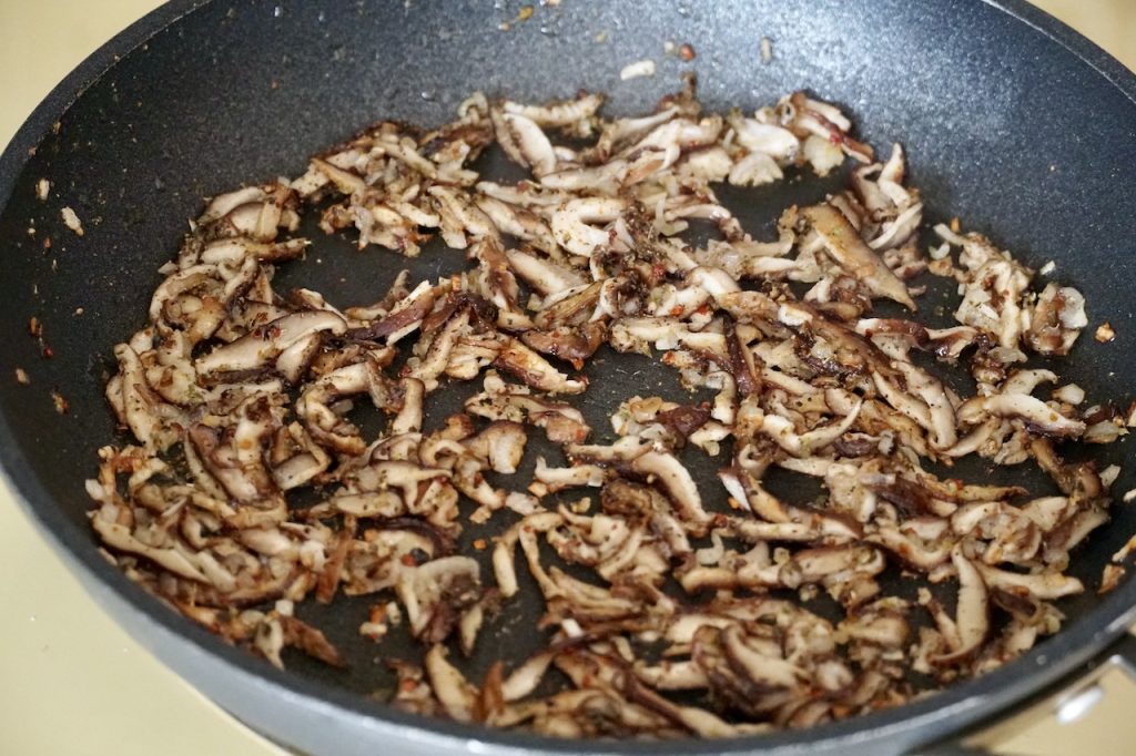 A skillet containing the sautéed sliced mushrooms and shallots.