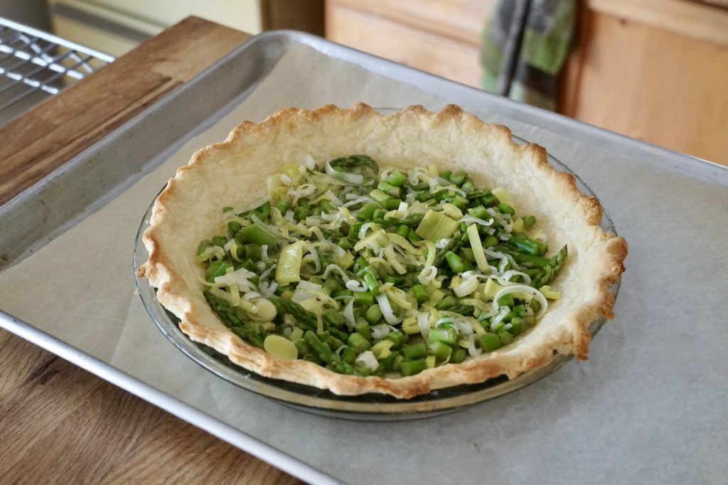 The sautéed leeks and asparagus transferred to the prepared quiche shell.