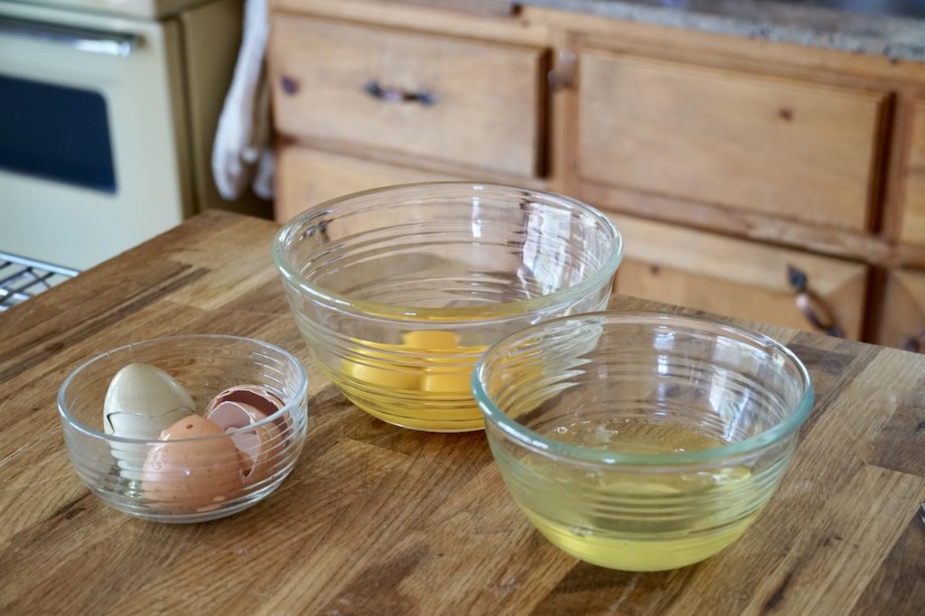 Fresh eggs separated into two bowls, one for yolks, the other for egg whites.