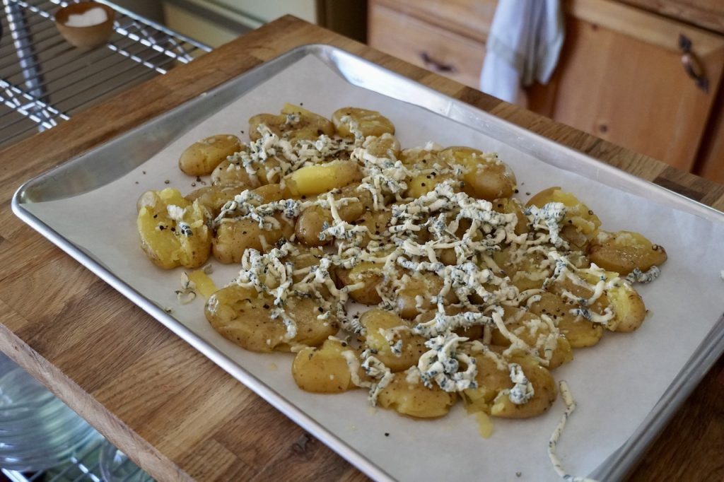 A baking tray of smashed potatoes ready for the oven.