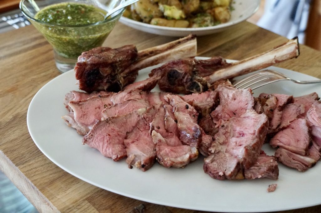 Grilled Veal Rib Chops served with tasty sides and a side of herbed chimichurri sauce.